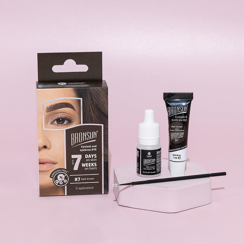 Eyelash and eyebrow dark brown dye tube, milk cream developer, and microbrush displayed with packaging aside