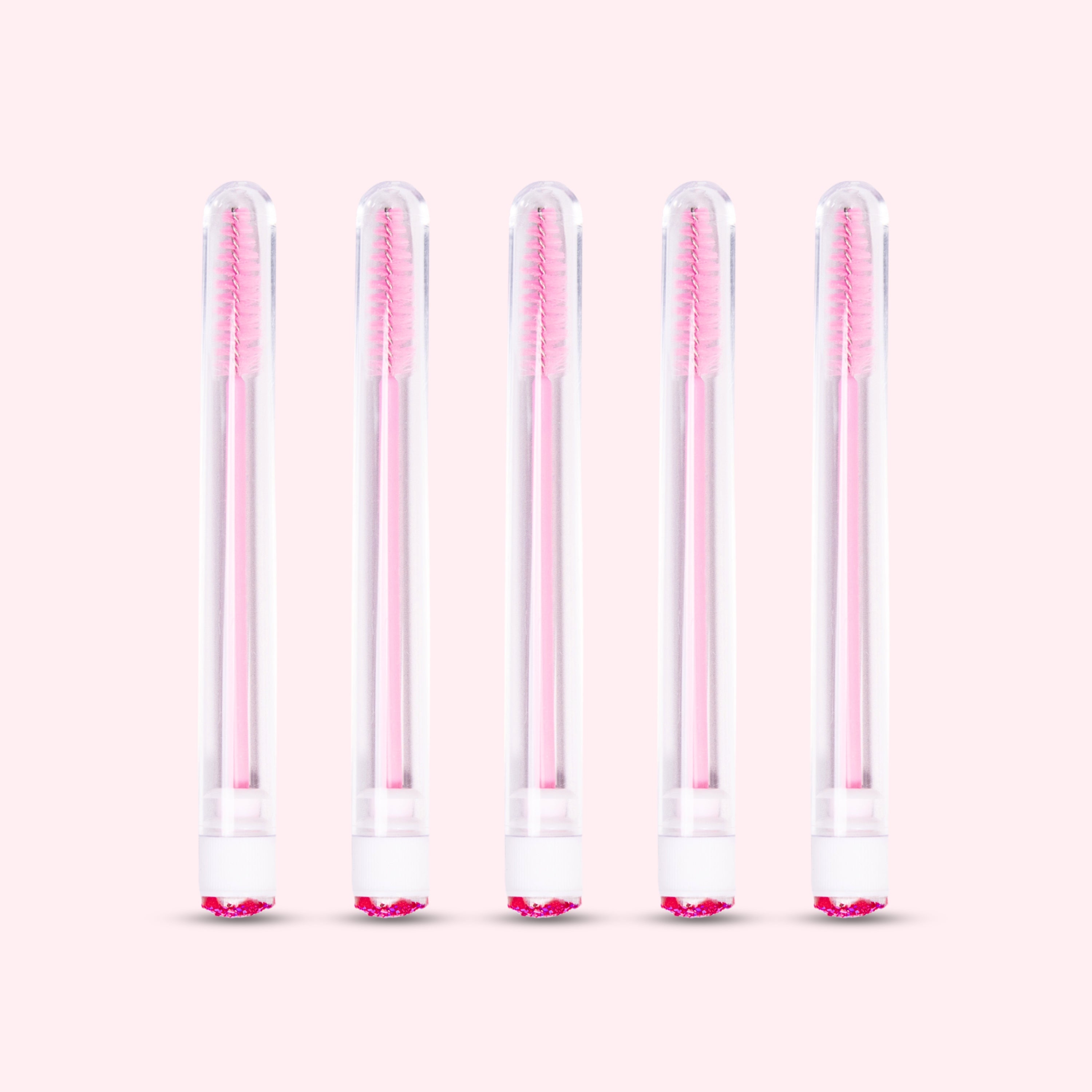 Five pcs Mascara Brushes with Tubes over a light pink background. 