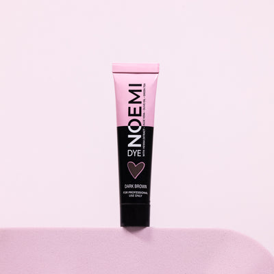 Noemi Hybrid Brow & Lash Dye - Dark Brown Bottle Over Pink Background