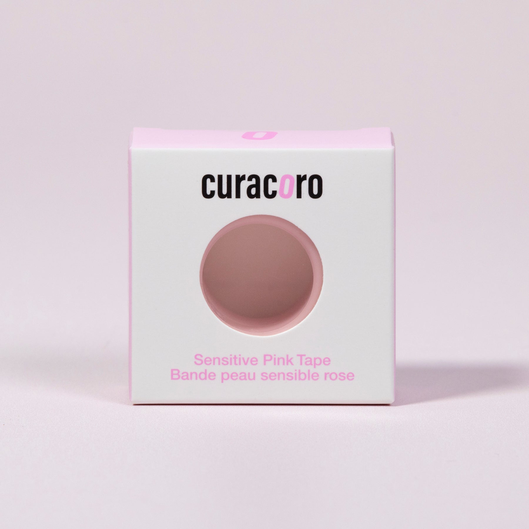 Curacoro sensitive pink tape for eyelash extensions in white and pink packaging, displayed on soft pink background