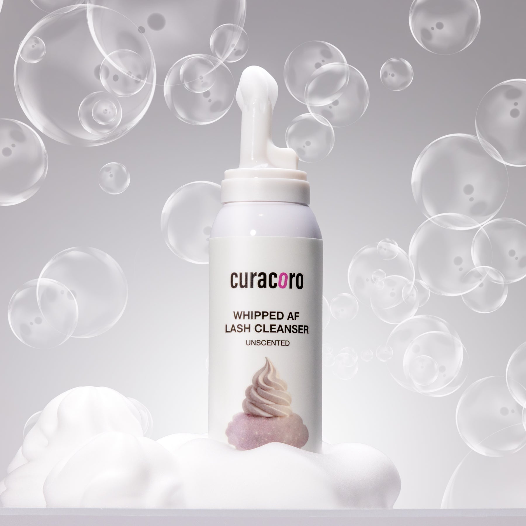 curacoro whipped AF lash cleanser bottle with bubbles and foam on a gray background