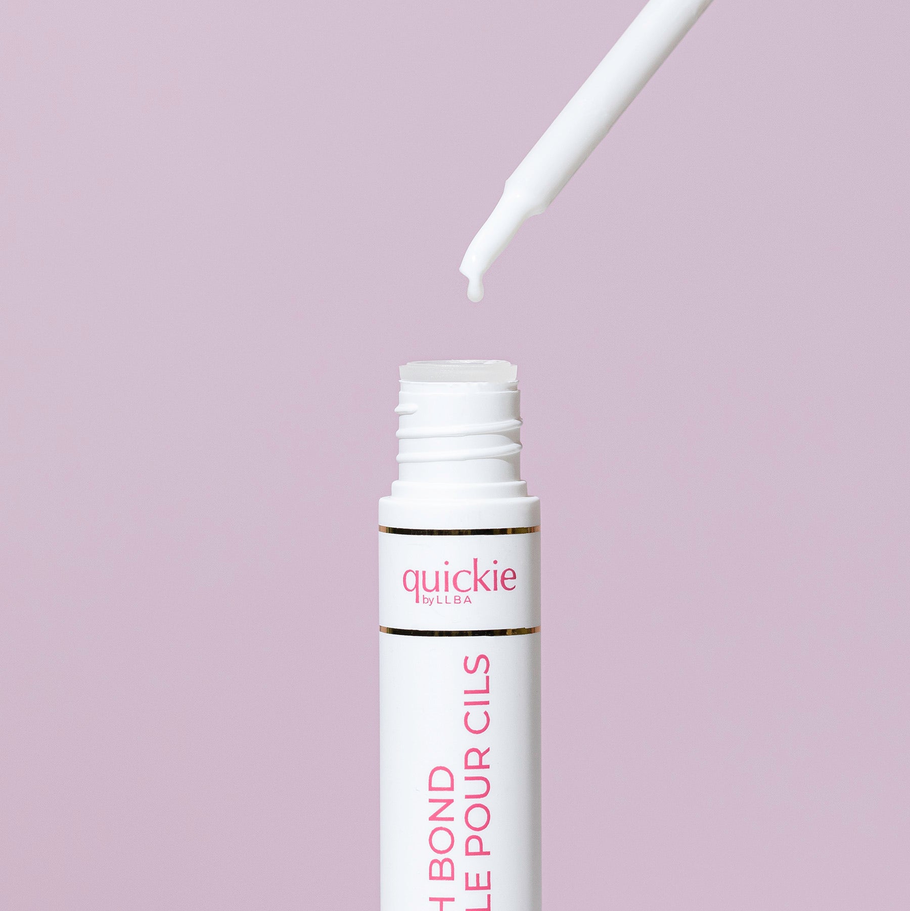 An open tube of lash bond with a white applicator dripping a small amount, set against a light purple background.