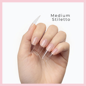 Curacoro Medium Sitletto Soft Gel Nail Tips on a hand, featuring natural nails with clear extensions, set against a white background with a pink border.