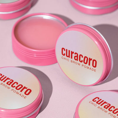 Curacoro Chic Brow Pomade with open case  in front of a pink background.