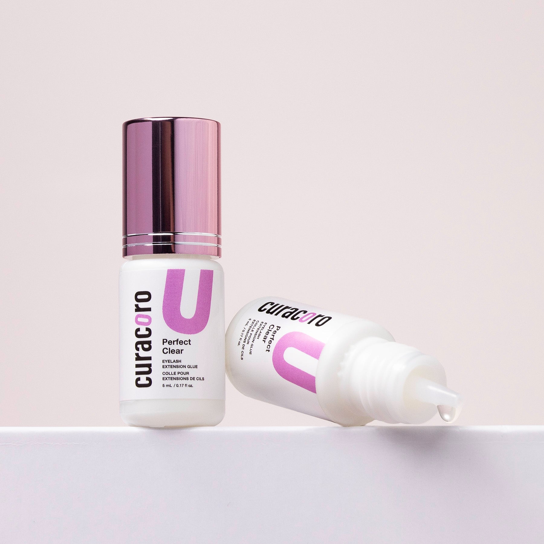 Curacoro Perfect Clear Eyelash Glue, 5mL bottle with purple cap and precision applicator, on neutral background.