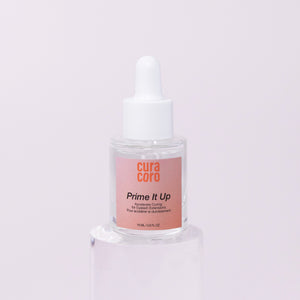 Curacoro Prime It Up accelerator for eyelash extensions, 15 ml dropper bottle on clear acrylic stand with soft pink background