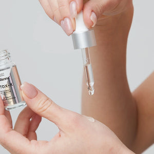Bottle of lash and brow botox held in hand with dropper and a drop of product
