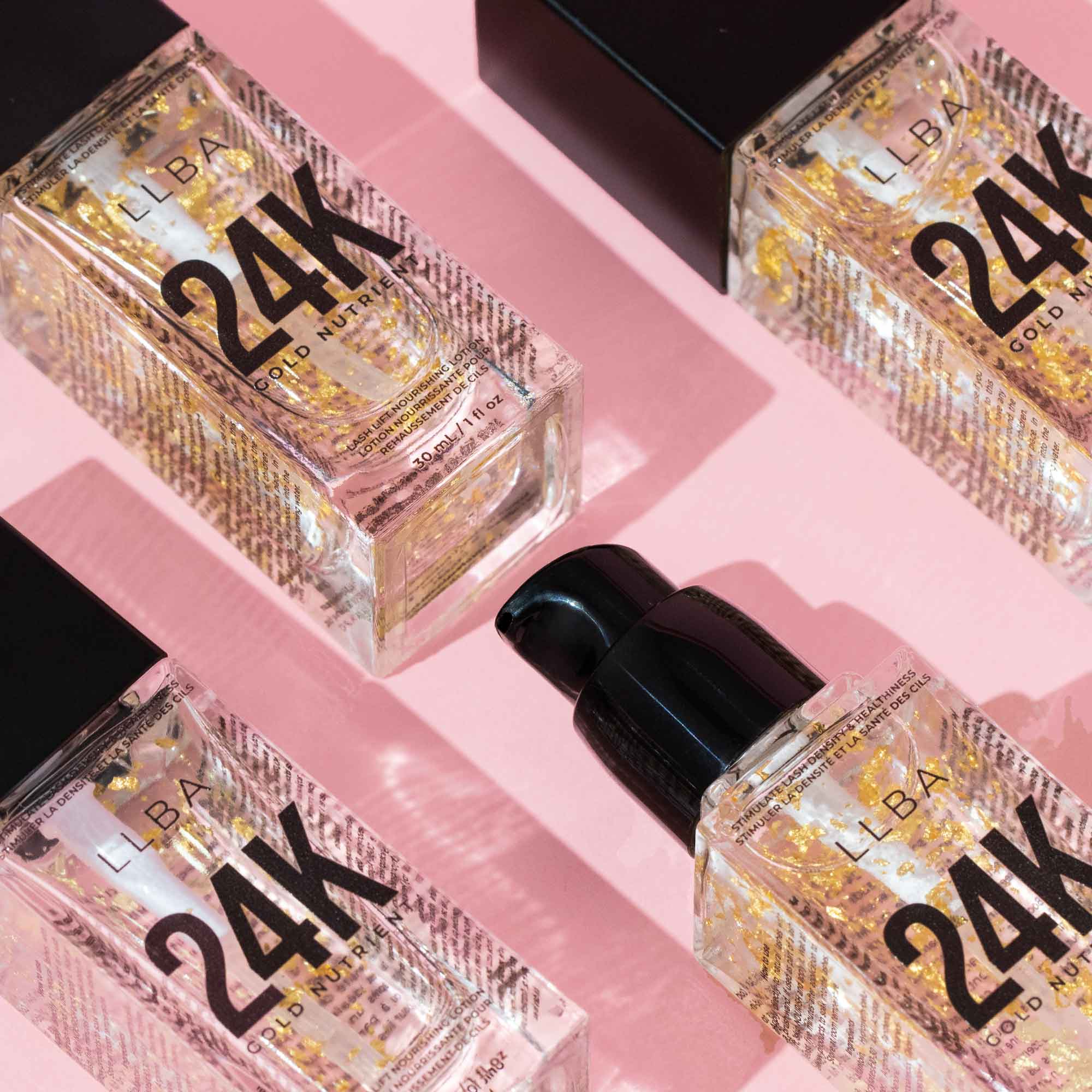Four bottles with gold flakes arranged on a pink background, casting shadows and reflecting light.