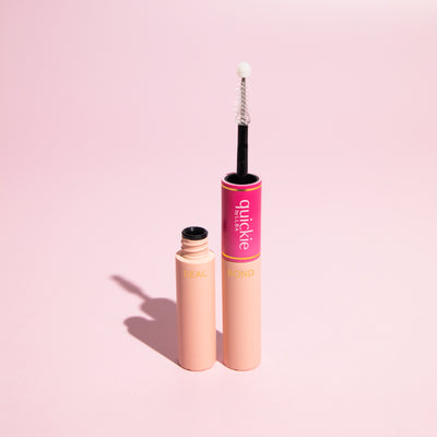 Close-up of 'Quickie by LLBA' lash adhesive with Seal and Bond components, featuring a white-tipped applicator on a pink background.