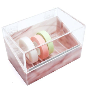 Acrylic tape dispenser with a pink marble base, featuring a clear lid and built-in serrated cutter, holding three rolls of medical-grade tape in white, pink, and green.